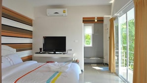 Ein Hotelzimmer mit Bett, Fernseher, Klimaanlage und einem Vorhangfenster.
