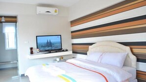 Ein Hotelzimmer mit einem Bett, einem Fernseher auf einem Schrank und einem gestreiften Kopfteil.
