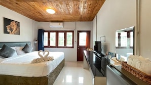 Quarto de hotel com cama, escrivaninha, televisão e um espelho grande.