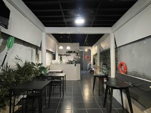 A restaurant interior with a central counter, black tiled floor, and potted plants. - Mook Boonchu Hotel (Ko Mook)