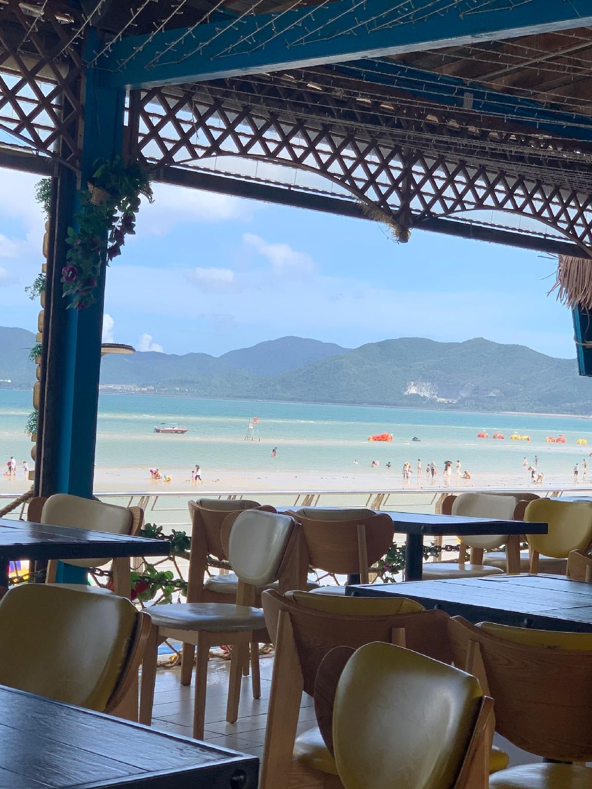 Un restaurante frente a la playa con terraza y vistas a la playa y las montañas.