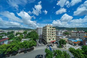 A cityscape with a prominent multi-story building, a crosswalk, and surrounding greenery. - Vienna Hotel (Shenzhen)