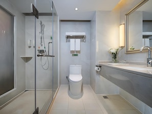 A modern bathroom with a glass-enclosed shower, a toilet, and a sink with a mirror. - Vienna Hotel (Shenzhen)