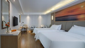 Ett hotellrum med två sängar, ett skrivbord med en stol, en TV och en tavla som föreställer en solnedgång.