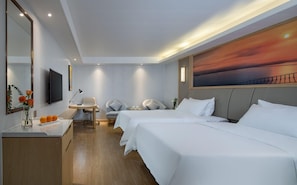 A hotel room with two beds, a desk with a chair, a TV, and a painting of a sunset. - Vienna Hotel (Shenzhen)
