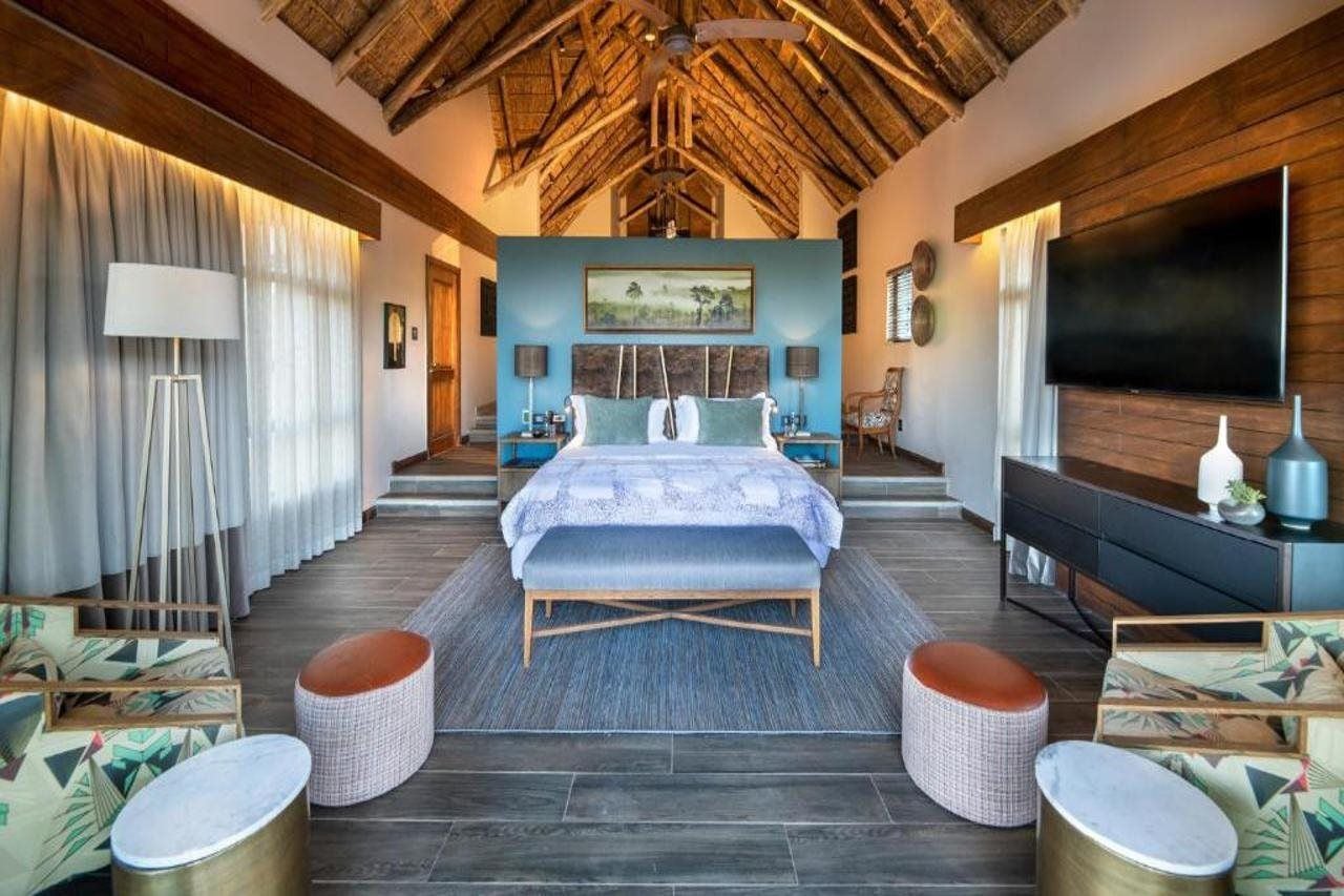 A spacious bedroom with a large bed, a flat-screen TV, and a ceiling fan.