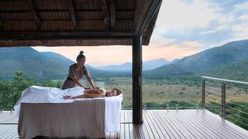 A massage therapy session on a wooden deck with a view of a mountainous landscape.