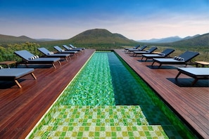 A pool with a clear view of the mountains, surrounded by lounge chairs.