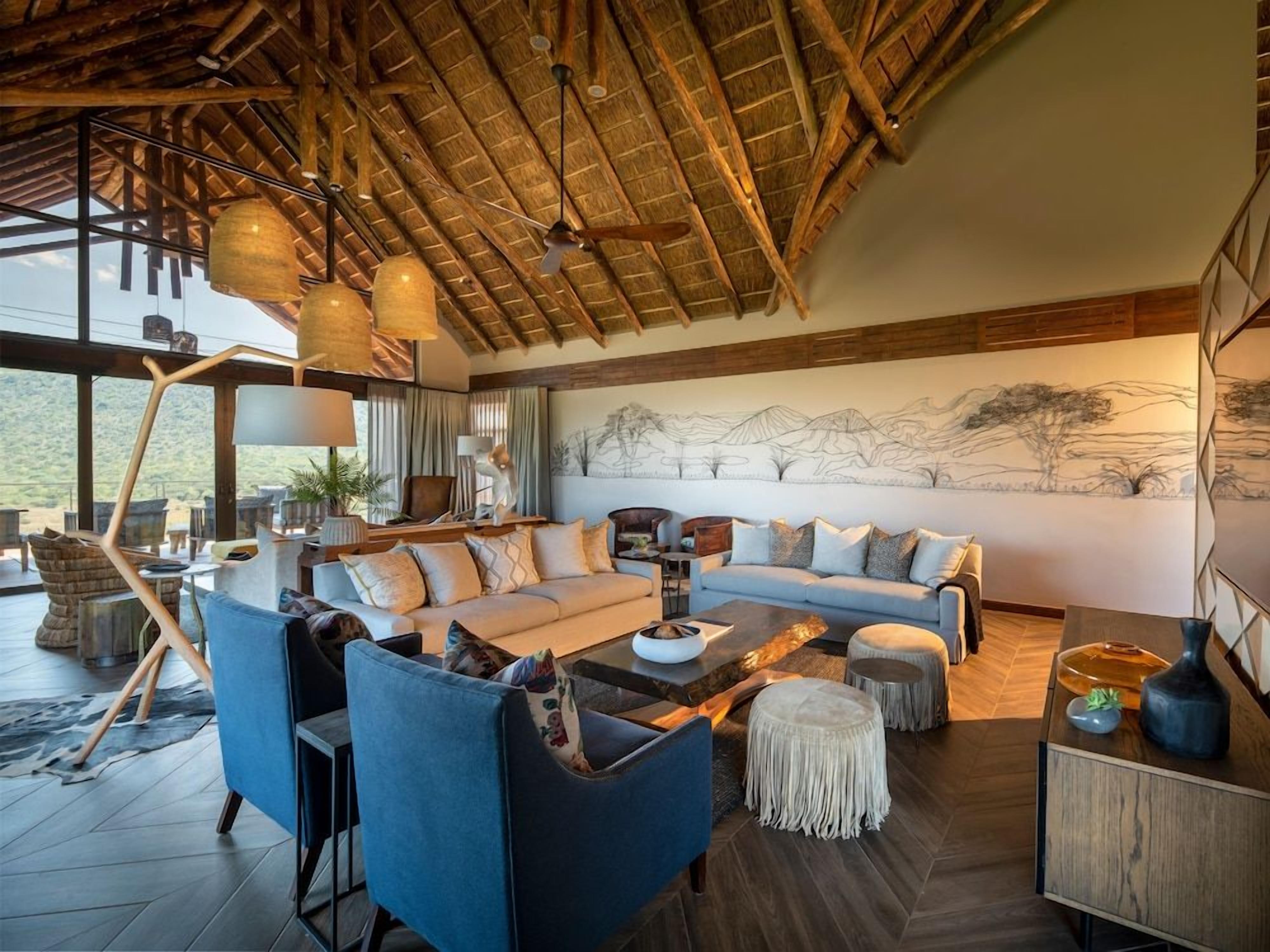 A spacious living area with a high ceiling, a large sofa set, and a dining table.