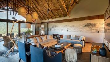 A spacious living area with a high ceiling, a large sofa set, and a dining table.