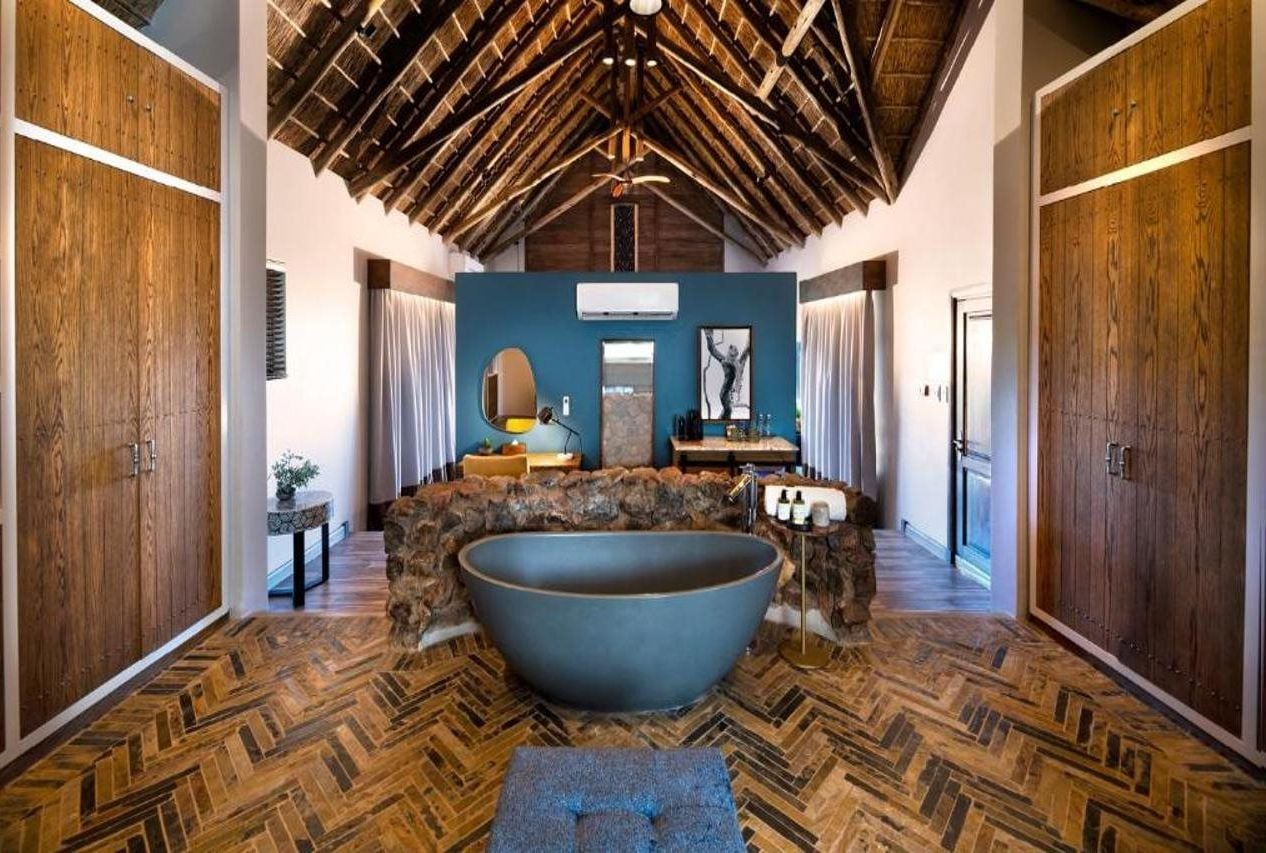A spacious bathroom with a large bathtub, wooden flooring, and a high ceiling with exposed beams.