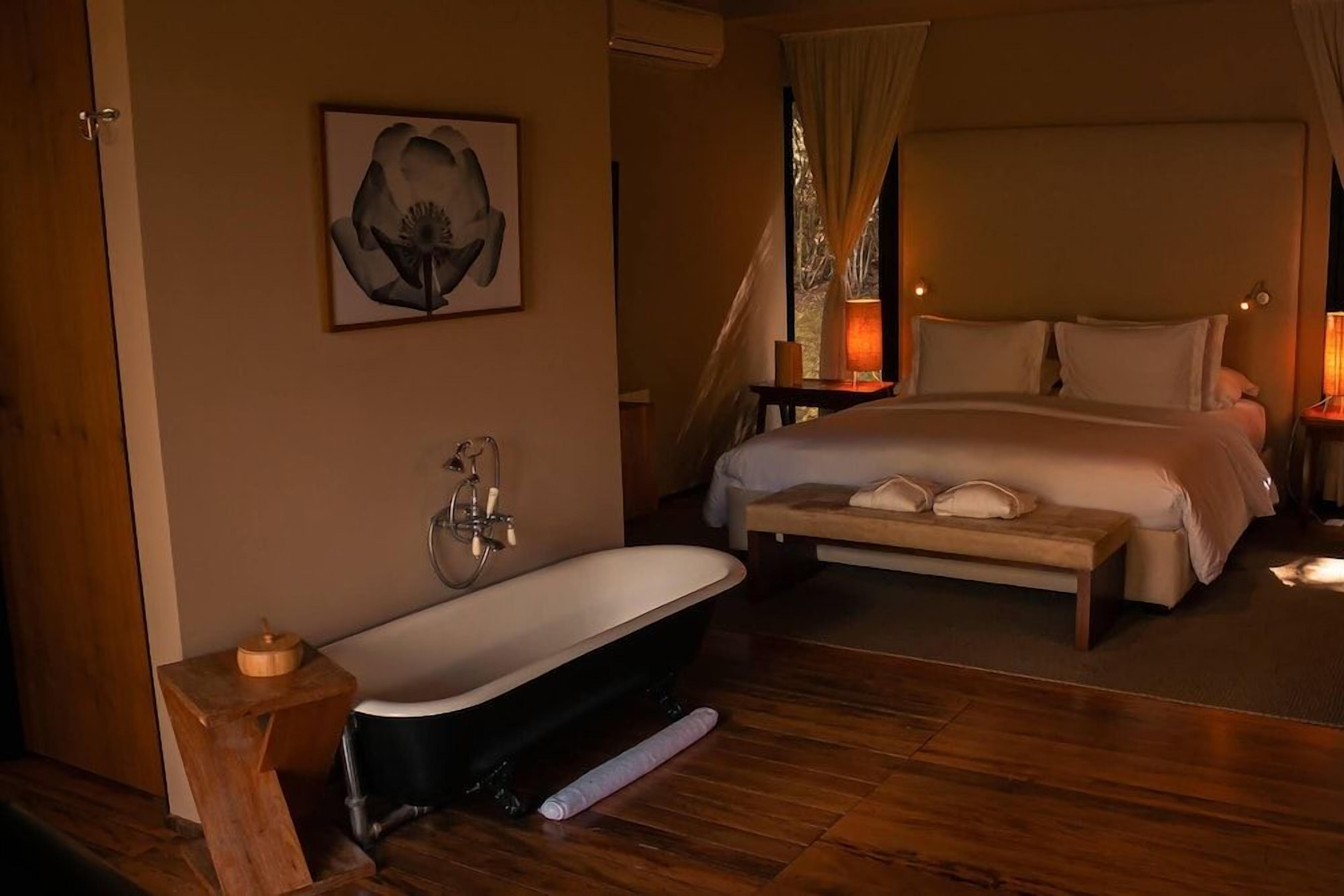 Un dormitorio con una cama grande, una bañera y un cuadro en la pared.