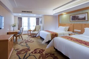 Quarto de hotel com duas camas, uma escrivaninha, uma cadeira e uma televisão.