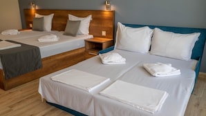 A hotel room with two beds, each with white linens and pillows, a wooden headboard, and a nightstand with a lamp. - Queen Nelly Park (Kiten)