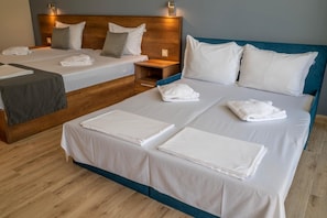 A hotel room with two beds, each with white linens and pillows, a wooden headboard, and a nightstand with a lamp. - Queen Nelly Park (Kiten)