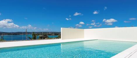 A swimming pool with a clear blue sky and distant mountains.