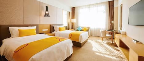 A hotel room with two beds, a desk, a chair, a television, and a window with curtains.