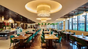 A spacious restaurant with multiple dining tables and chairs, a central chandelier, and large windows providing natural light. - Club Med Joyview Beijing Yanqing (Beijing)