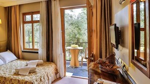 A hotel room with a bed, a small table with a basket, a TV, and a window with curtains. - Club Gultur Otel (Ayvacik)
