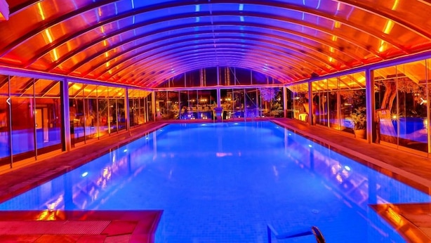 An indoor swimming pool with a glass ceiling and a view of the cityscape. - Club Gultur Otel (Ayvacik)