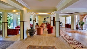 A spacious lobby with a high ceiling, a central seating area with red chairs, and a patterned carpet. - Club Gultur Otel (Ayvacik)
