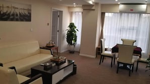 A living room with a sofa, a coffee table, a potted plant, and a painting on the wall. - West Mansion Hotel Beijing (Beijing)