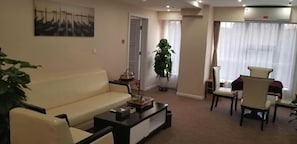 A living room with a sofa, a coffee table, a potted plant, and a painting on the wall. - West Mansion Hotel Beijing (Beijing)