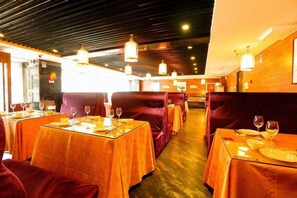A restaurant with tables set for dining, featuring a warm color scheme and modern lighting fixtures. - West Mansion Hotel Beijing (Beijing)
