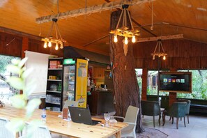 Interior em madeira com área de bar, um tronco de árvore grande e uma tela de televisão.