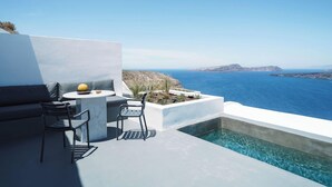 Zona relax esterna moderna con piscina, vista su un paesaggio costiero.