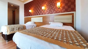 Een hotelkamer met twee bedden, een houten hoofdbord en wandlampen.