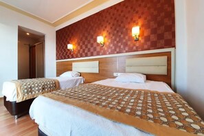 Une chambre d’hôtel avec deux lits, une tête de lit en bois et des lampes fixées au mur.