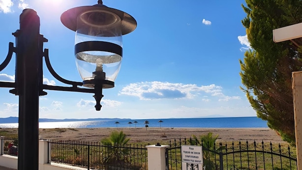 Uitzicht op het strand, met een heldere lucht, een lantaarnpaal en een bord dat een openbaar gebied aangeeft.