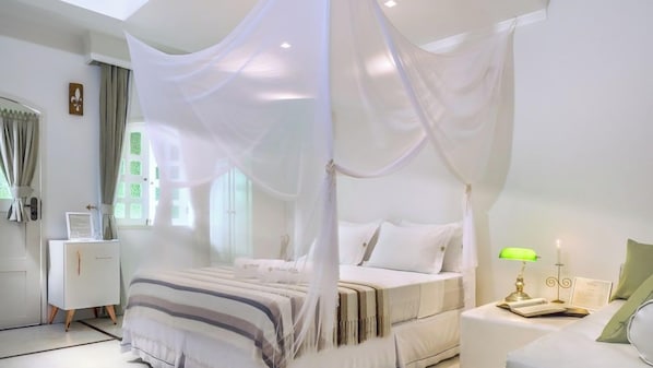 A bedroom with a canopy bed, bedside table with a lamp, and a nightstand with a book. - Mona Lisa Pousada (Jijoca de Jericoacoara)