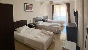 A hotel room with three beds, a television, a desk, and a refrigerator. - Altinkum Tatil Konaklari (Marmara)