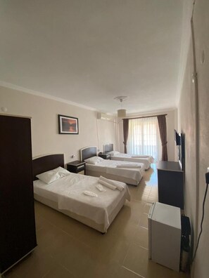 Une chambre d’hôtel avec trois lits, une télévision, un bureau et un réfrigérateur.