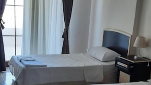 A hotel room with two beds, a nightstand, a lamp, and a window with curtains. - Altinkum Tatil Konaklari (Marmara)