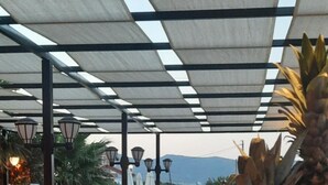 An outdoor seating area with tables and chairs, a pool, and a fruit bowl on a table. - Altinkum Tatil Konaklari (Marmara)