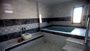 Un baño con piso de mármol, una bañera, un lavabo y una ventana.