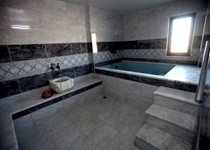 Un baño con piso de mármol, una bañera, un lavabo y una ventana.