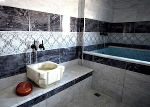 Un baño con pared de mármol, una bañera y un inodoro.