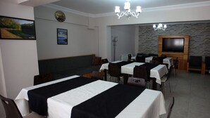Un comedor con mesas dispuestas para el servicio, un televisor montado en una pared de piedra y un reloj en la pared.