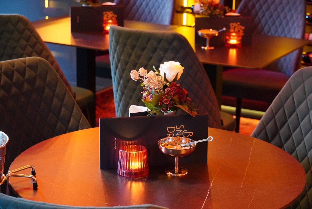 A dining table with a candle, a small bowl, and a menu.