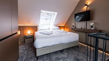 Un dormitorio moderno con cama, lámparas de noche, televisor y ventana.