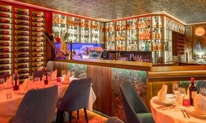 Eine Bar mit Regalen voller Flaschen und Gläsern, einer Uhr und Tischen, die zum Essen gedeckt sind.