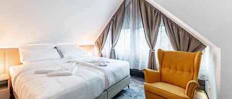 Una habitación de hotel con cama, una silla y una ventana con cortinas.