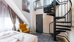 Un dormitorio con cama, una silla, una puerta y una escalera de caracol.
