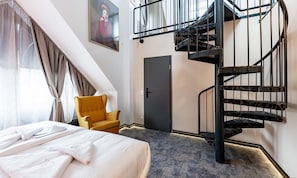 Ein Schlafzimmer mit einem Bett, einem Sessel, einer Tür und einer Wendeltreppe.