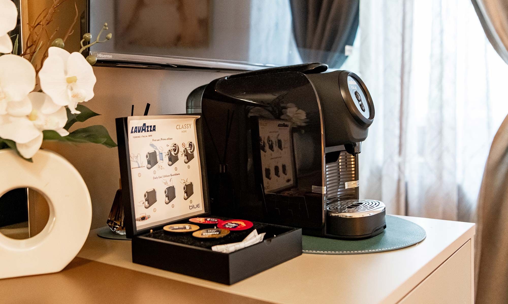 Una cafetera sobre una mesa con un manual y una caja de cápsulas de café.