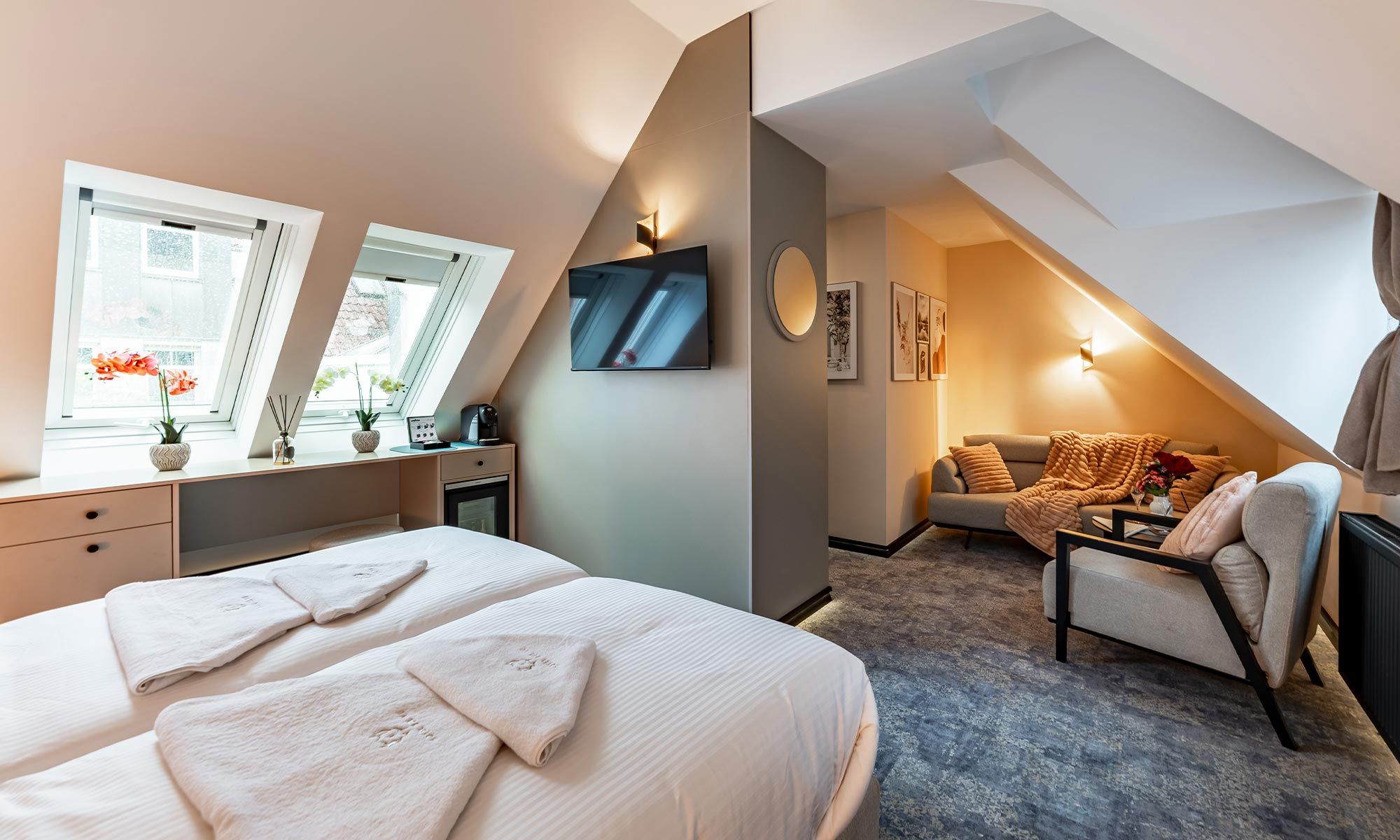 A bedroom with a bed, a desk, a chair, a TV, and a sofa.